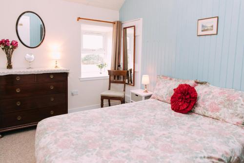 a bedroom with a bed and a dresser and a mirror at Incheoch Farm Cottage in Kilry