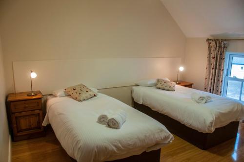 een slaapkamer met 2 bedden en handdoeken bij Finn Cottage in Strabane
