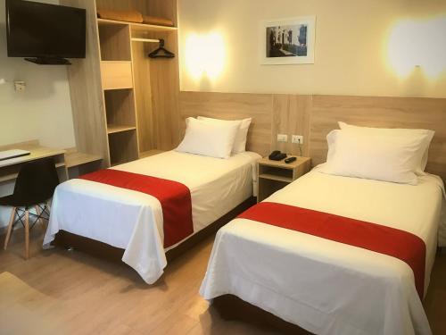 a hotel room with two beds and a desk at Hotel San Remo in Lima