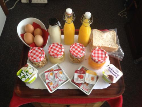 a table with eggs eggs bread and bottles of orange juice at Lakefront Lodge in Te Anau