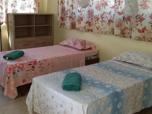 Dos camas en una habitación con toallas verdes. en Pension Turiroa " Chez Olga" en Avatoru