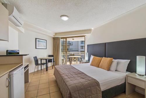 um quarto de hotel com uma cama grande e uma cozinha em BreakFree Alexandra Beach em Alexandra Headland