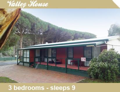 a red and green building with a mountain in the background at Second Valley Caravan Park in Second Valley