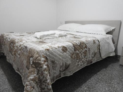 a bed with a blanket and pillows on it at Soggiorno Ulivi in Altino