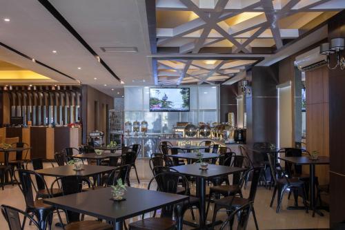 un restaurante con mesas y sillas y un bar en JLE'S Hotel, en Manado