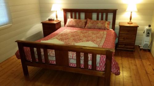 a bedroom with a wooden bed and two night stands at About Town Cottages in Broken Hill