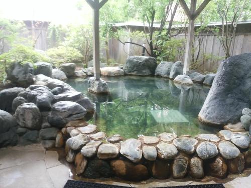 a pool of water with rocks in a garden at Royal Hotel Kawaguchiko in Fujikawaguchiko