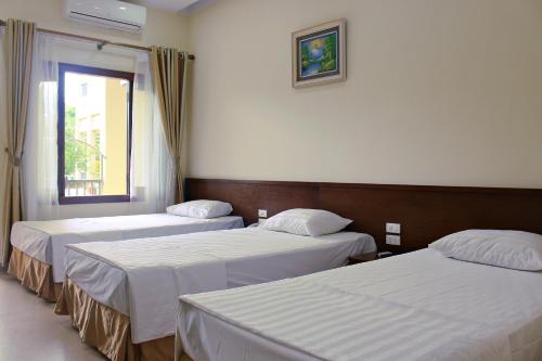 two beds in a hotel room with a window at Hanvet Hotel Do Son in Ðố Sơn