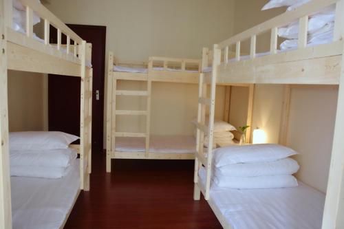 a room with three bunk beds with white pillows at Lan House Youth Apartment in Guangzhou
