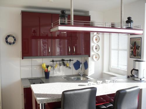 Apartment Sonnenschein في برونلاغ: مطبخ بدولاب حمراء وقمة بيضاء