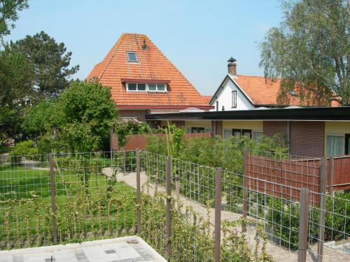 a house with a fence and a building behind it at Pension Kamperland in Kamperland