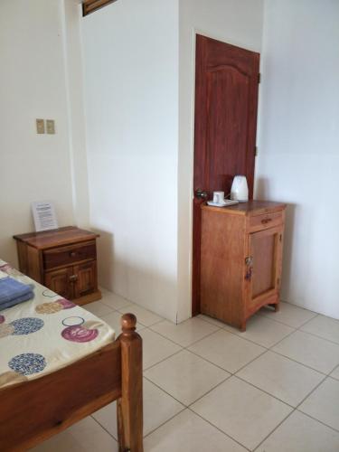 a room with a bed and a table and a wooden cabinet at Anton's Beach Resort in Oslob