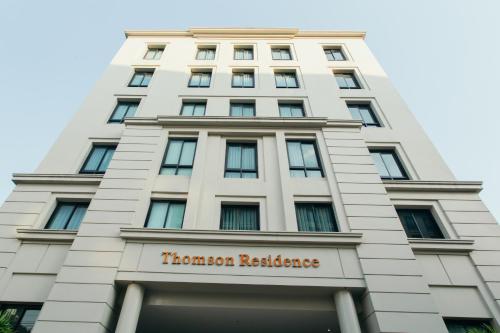 een hoog wit gebouw met een bord erop bij Thomson Residence Hotel in Bangkok