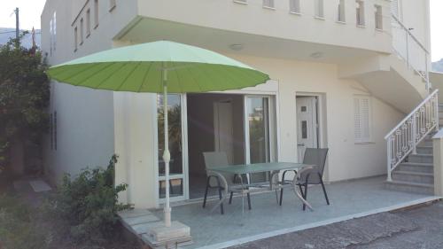 a green umbrella on a patio with a table and chairs at Beautiful home in Káto Pitsá