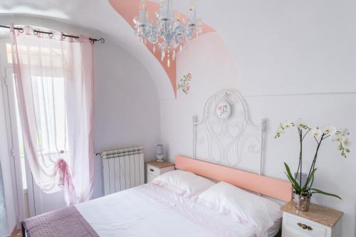 um quarto com uma cama branca e um lustre em DUSSAIGA - Camera Delle Rose em Dolceacqua