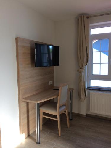 a room with a desk with a television on a wall at Hotel Mezzero in Waldshut-Tiengen