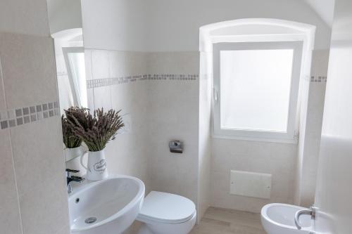 un bagno bianco con un water e un lavandino di DUSSAIGA - Camera Delle Rose a Dolceacqua