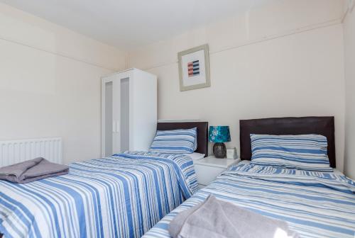 two beds sitting next to each other in a room at DAGENHAM 3 and 4 BEDROOMS 2BATHS with Parking in Dagenham