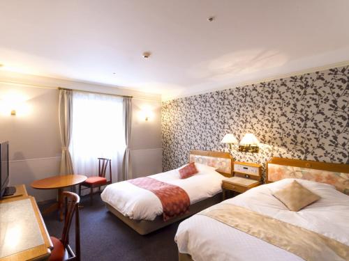 a hotel room with two beds and a window at Hotel Merieges in Miyazaki
