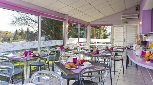 un restaurant avec des tables, des chaises et des fenêtres dans l'établissement Tourhotel Blois, à La Chaussée-Saint-Victor