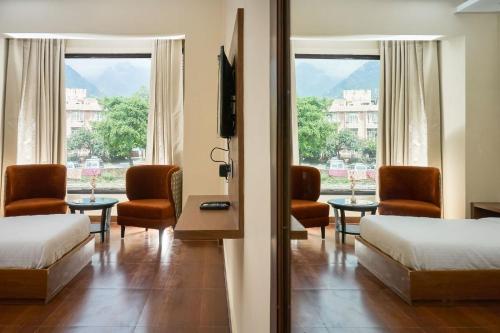 a hotel room with two beds and a television at Ganpati Hotel Katra in Katra