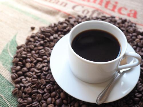 a cup of coffee sitting on top of coffee beans at Paper Moon in Nasu