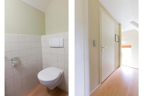 a bathroom with a white toilet and a door at Idyllic Lakehouse - dog is welcome fenced garden in Haren