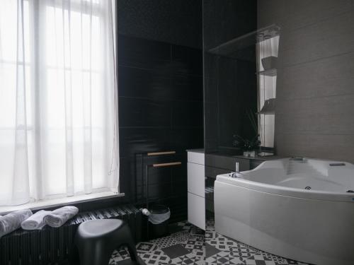 La salle de bains est pourvue d'une baignoire, d'un lavabo et d'une fenêtre. dans l'établissement Une maison en ville, Hyper Centre ville, Spa, à Amiens