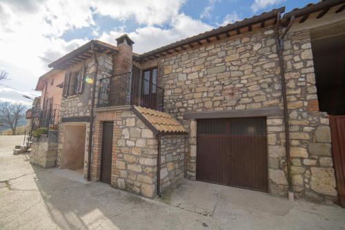 una casa de piedra con una puerta y un garaje en La Fattoria dei Sibillini, en Montemonaco