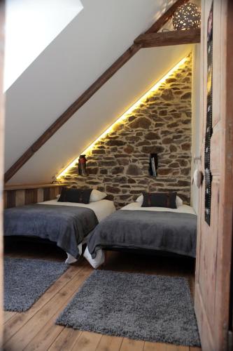 - 2 lits dans une chambre avec un mur en pierre dans l'établissement Maison A Babord Plage, à Saint-Quay-Portrieux