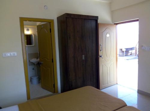 a bedroom with a door leading to a bathroom at Suvarna Compact in Mysore