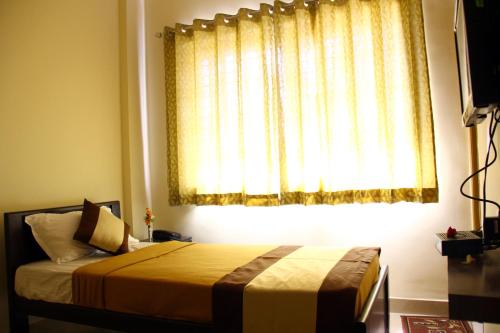 a bedroom with a bed in front of a window at Suvarna Compact in Mysore