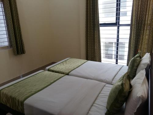 two beds in a bedroom with a window at Suvarna Compact in Mysore