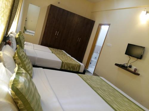 a hotel room with two beds and a television at Suvarna Compact in Mysore