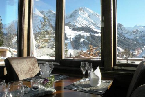 a table with glasses and a view of a mountain at Hotel Steinmattli in Adelboden