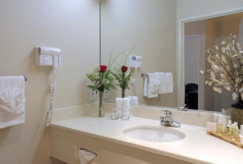 a bathroom with a sink and a mirror and flowers at Holiday Inn Express & Suites - Tulare, an IHG Hotel in Tulare