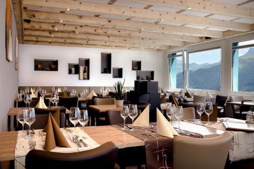 una sala da pranzo con tavoli, sedie e finestre di Hotel Hohe Promenade a Arosa