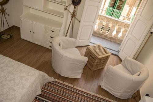 una camera da letto con sedie bianche, un letto e una finestra di Vincenti Strait Street Suite a La Valletta