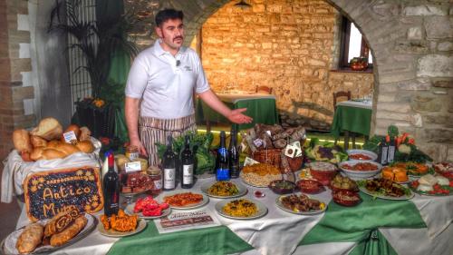 a man standing in front of a table of food at Agriturismo Antico Muro in Sassoferrato