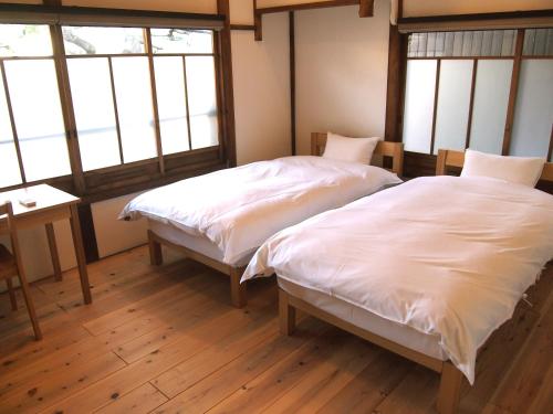 2 Betten in einem Zimmer mit 2 Fenstern in der Unterkunft Ichimatsu-an in Kyoto