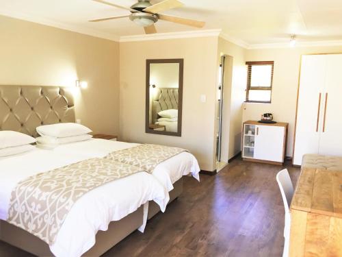 a bedroom with a bed and a ceiling fan at Loerie Guest Lodge in George