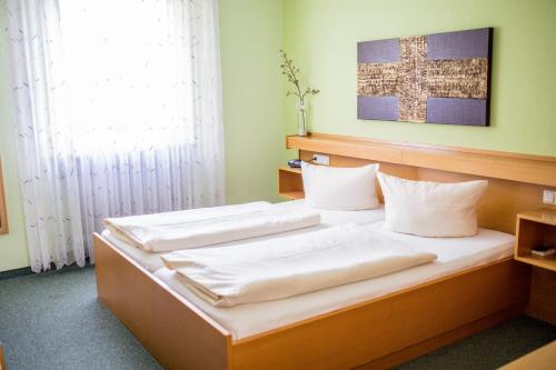 1 Schlafzimmer mit 2 Betten und weißen Kissen in der Unterkunft Hotel-Restaurant Wiendl in Regensburg