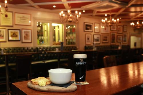 a glass of beer and a bowl on a table in a restaurant at Mellon Country Inn Hotel in Omagh