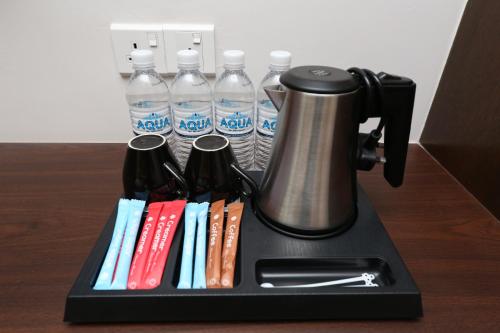 a coffee maker on a black tray with water bottles at M&M Hotel in Kuala Lumpur