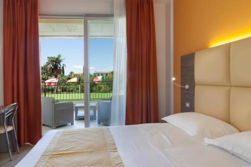 a bedroom with a bed and a view of a balcony at Hotel Bella Lazise in Lazise