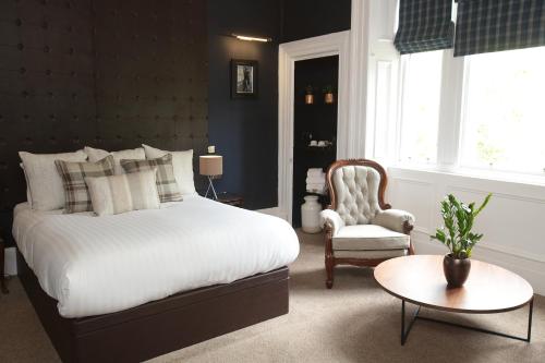 a bedroom with a bed and a chair and a table at The Belhaven Hotel in Glasgow