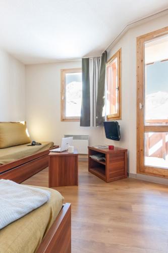 Cette chambre comprend deux lits, un bureau et une télévision. dans l'établissement Résidence Pierre & Vacances Les Temples du Soleil, à Val Thorens
