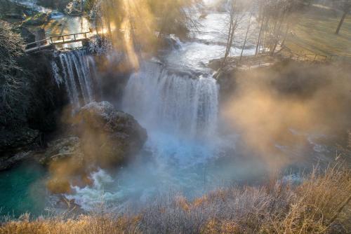 a waterfall with smoke coming out of it next to a field at Apartment Kolaković in Slunj