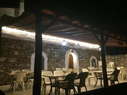 a restaurant with tables and chairs and a stone wall at Posada El Parral in Benaocaz