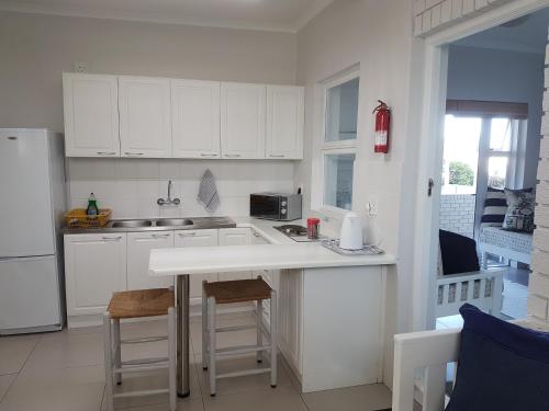 a white kitchen with a sink and a refrigerator at South Point Guest Lodge in Agulhas